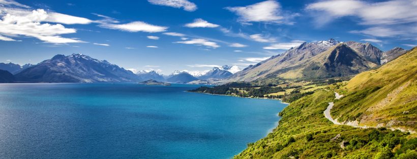 vista of mountains, a lake, and dirt road